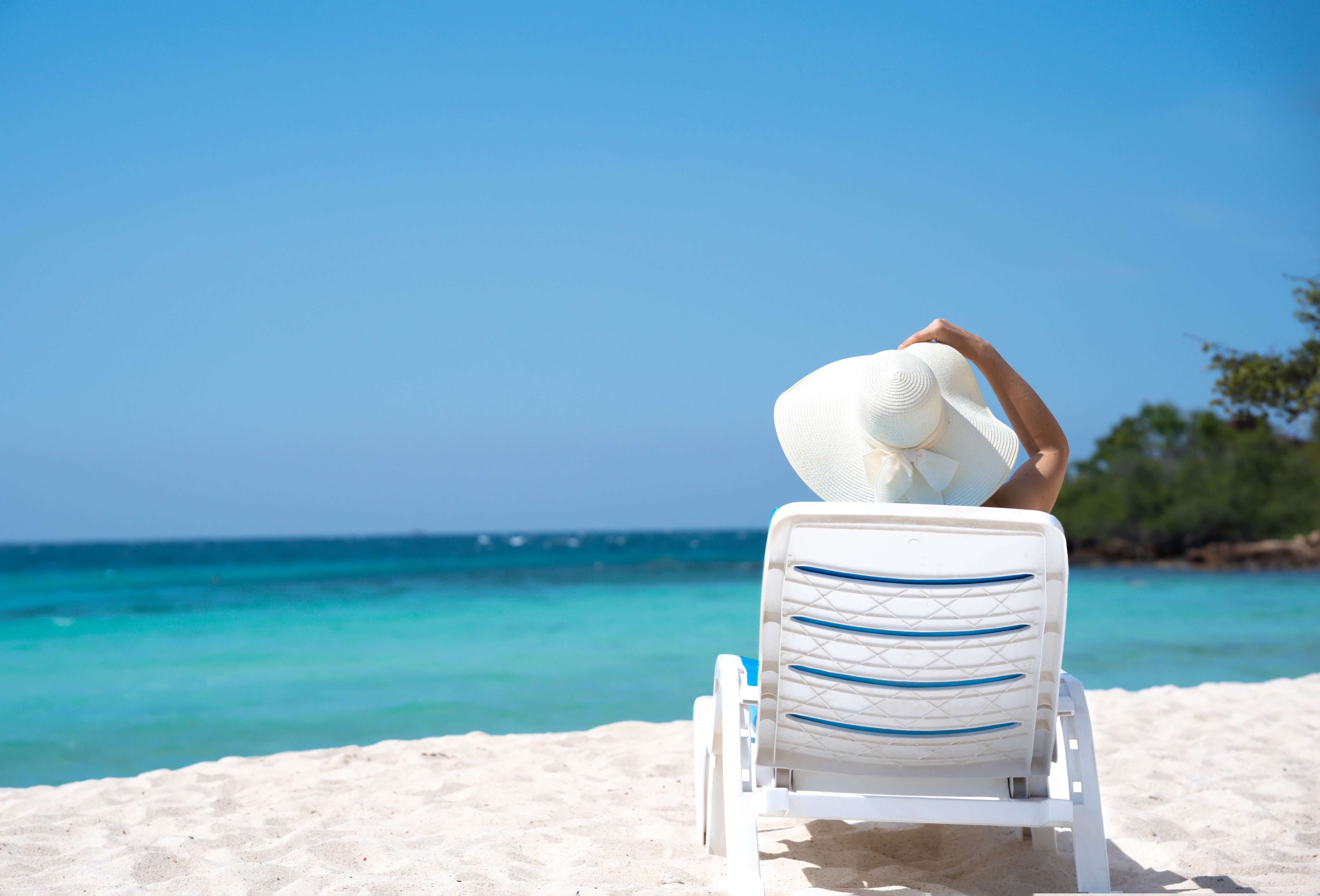 A woman sitting on a beach in a hat